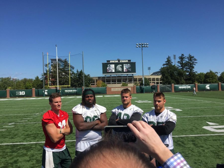 Brian Lewerke, Raequan Williams, Kenny Willekes, and Joe Bachie pose for a photo at media availability. 