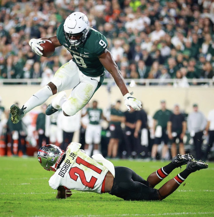 MSU running back Kenneth Walker hurdles Western Kentucky safety Beanie Bishop in the Spartans 48-31 win over the Hilltoppers on Oct. 2, 2021/ Photo Credit: MSU Athletic Communications 