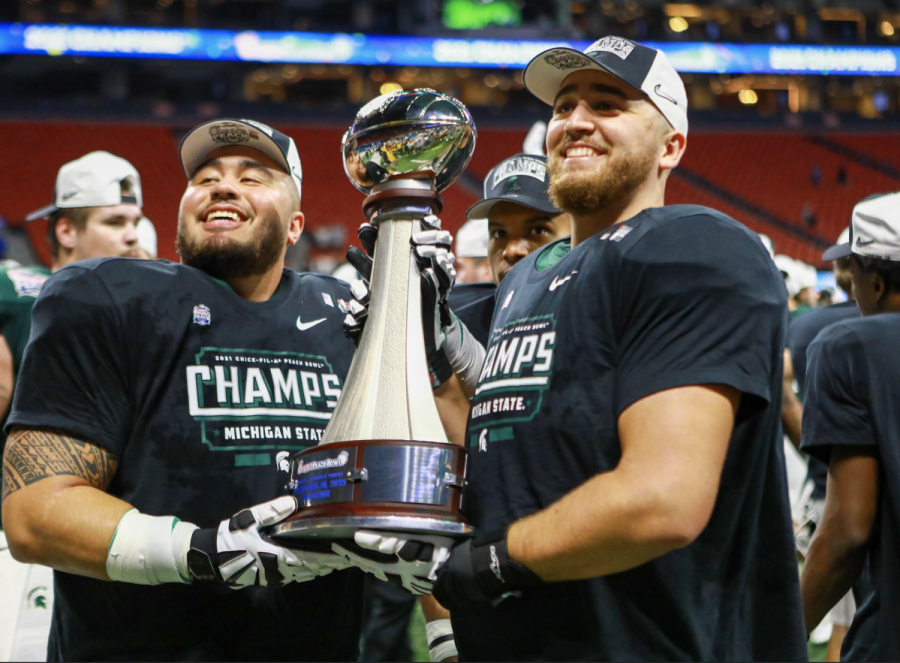 MSU offensive guard Jacob Isaia (left) and offensive tackle Dan VanOpstall hold the 2021 Peach Bowl trophy after knocking off No. 12 Pittsburgh/ Photo Credit: MSU Athletic Communications
