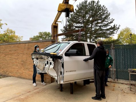 Cab of therapy car is on a lift while the team stands next to it