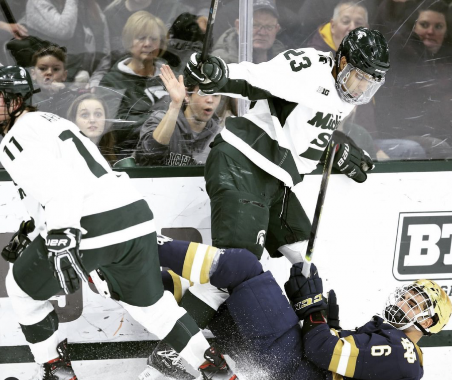 MSU+forward+Jagger+Joshua+lays+out+a+Notre+Dame+hockey+player%2F+Photo+Credit%3A+MSU+Athletic+Communications+