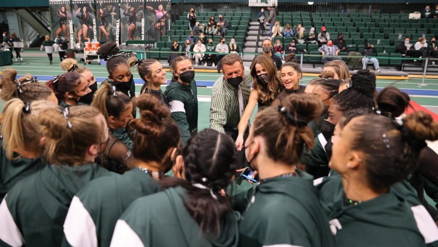 Michigan State women's gymnastics coach Mike Rowe and his team huddle up in competition against Illinois/Photo Credit: MSU Athletic Communications