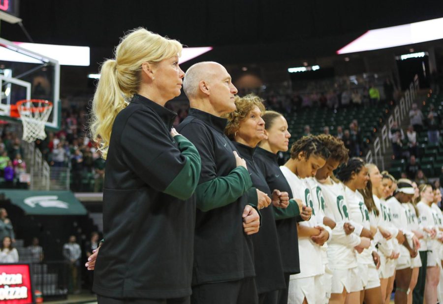 Head+coach+Suzy+Merchant+and+her+team+stand+for+the+national+anthem.+Photo+credit%3A+Sarah+Smith%2FWDBM
