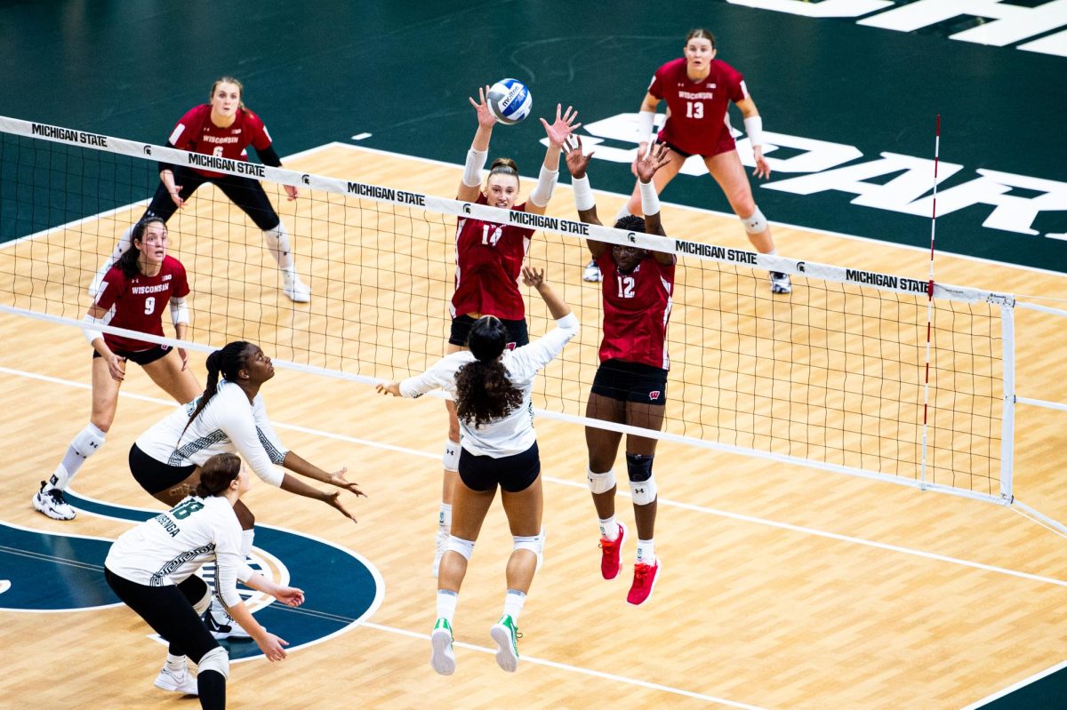 MSU junior outside hitter Aliyah Moore rises to hit the ball over the Wisconsin defense on Friday, October 27, 2023 at the Breslin Center.