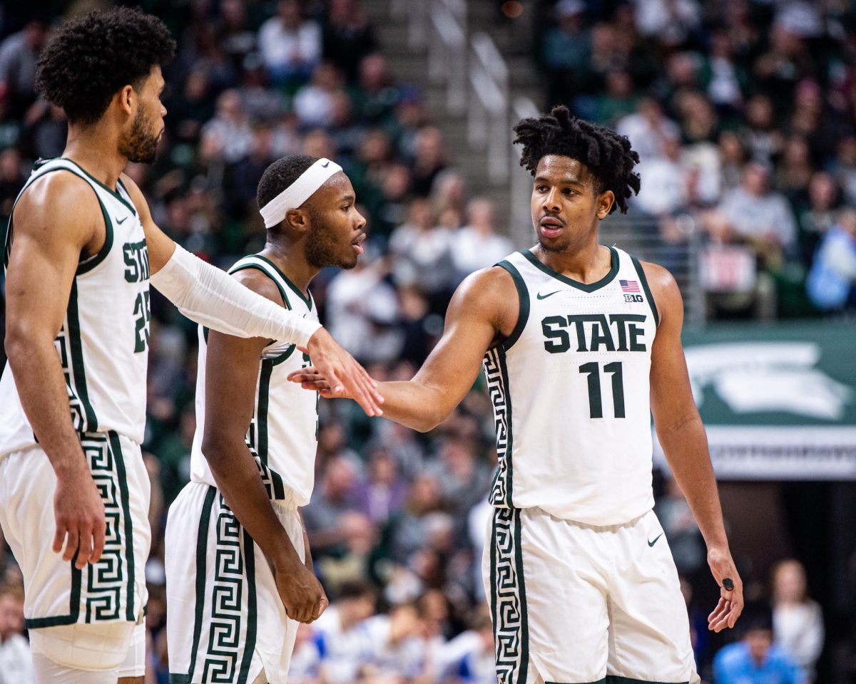 MSU senior guard A.J. Hoggard (11) celebrates with graduate forward Malik Hall (left) and sophomore guard Tre Holloman after scoring against Indiana State on Saturday, December 30, 2023 at the Breslin Center.