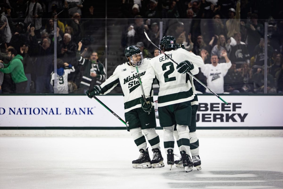MSU freshman defender Patrick Geary (2) celebrates with sophomore forward Tiernan Shoudy (13) after a Spartan goal in a 5-4 overtime victory over Michigan for the B1G Championship on Saturday, Mar. 23, 2024 at Munn Ice Arena. (Avery Kotel)