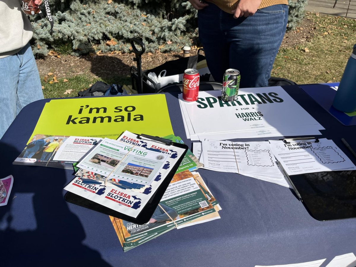 A table with posters and flyers advocating for the Harris/Walz ticket ran by College Democrats at MSU. Photo Credit: Maco Jeleniewski/WDBM